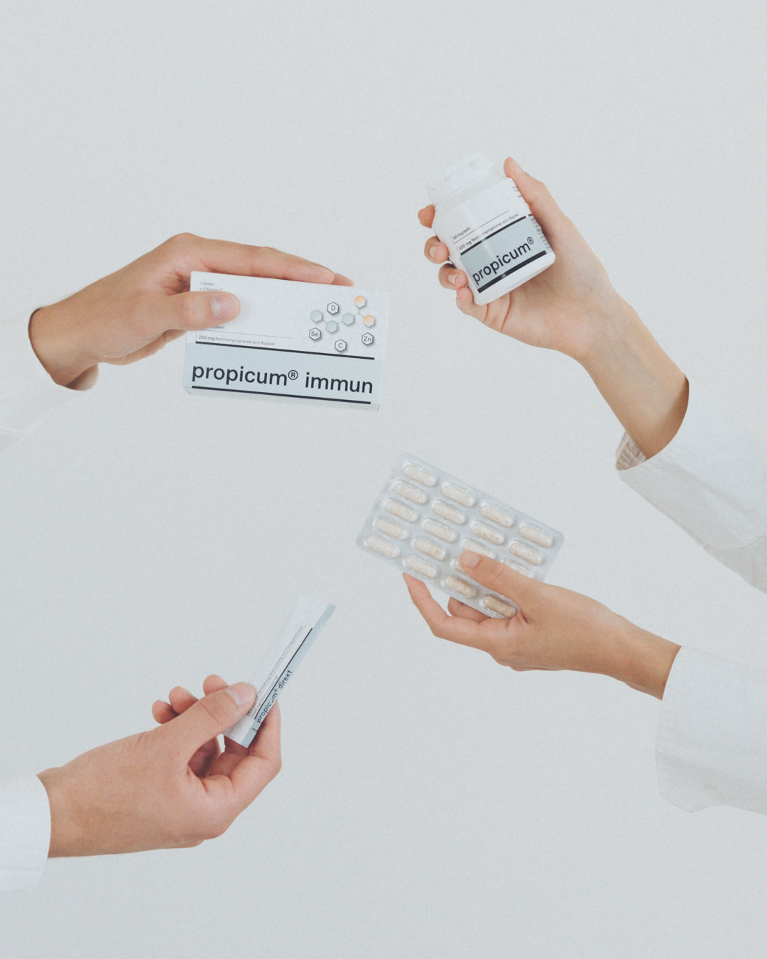 Vier Hände halten verschiedene Produkte der Marke propicum® immun: eine Tablettenverpackung, eine Kapseldose, eine Blisterpackung und einen Einzelstick.