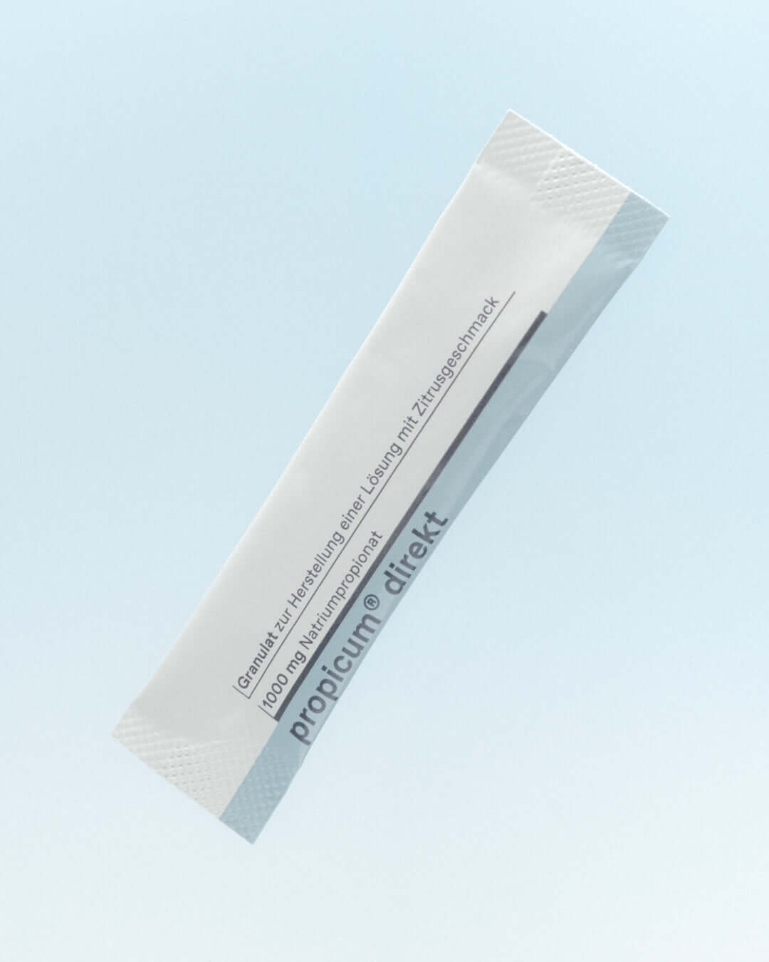 Einzelnes Sachet 'propicum direkt' mit Granulat zur Herstellung einer Zitronenlösung. Weißes Sachet mit hellblauem Streifen, 1000 mg Natriumpropionat, schwebend vor hellblauem Hintergrund.