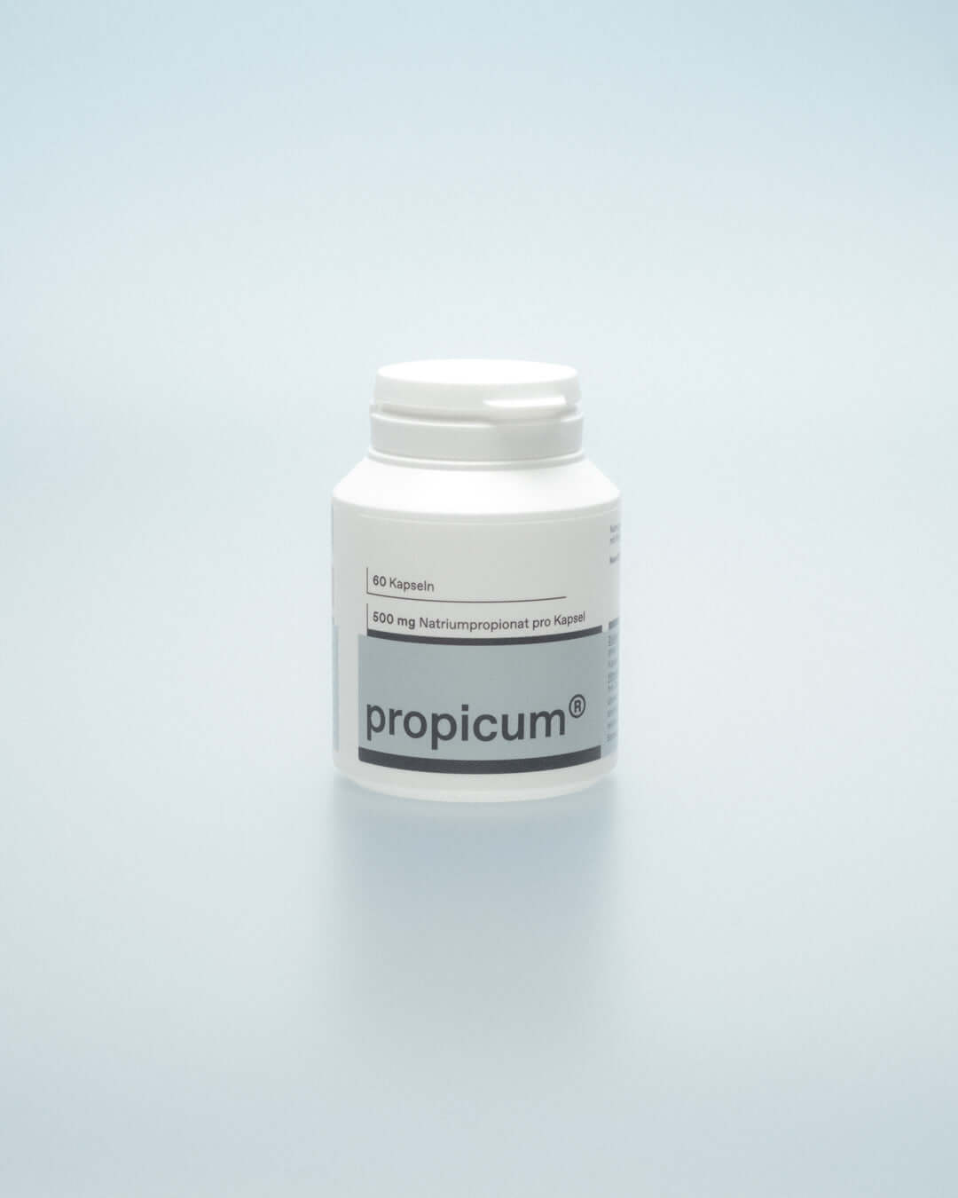 Weißer Behälter mit Schraubverschluss auf hellblauem Hintergrund. Etikett zeigt ‚propicum®‘ und ‚500 mg Natriumpropionat pro Kapsel‘. Schlichte, moderne Verpackung, die sich klar vom Hintergrund abhebt.