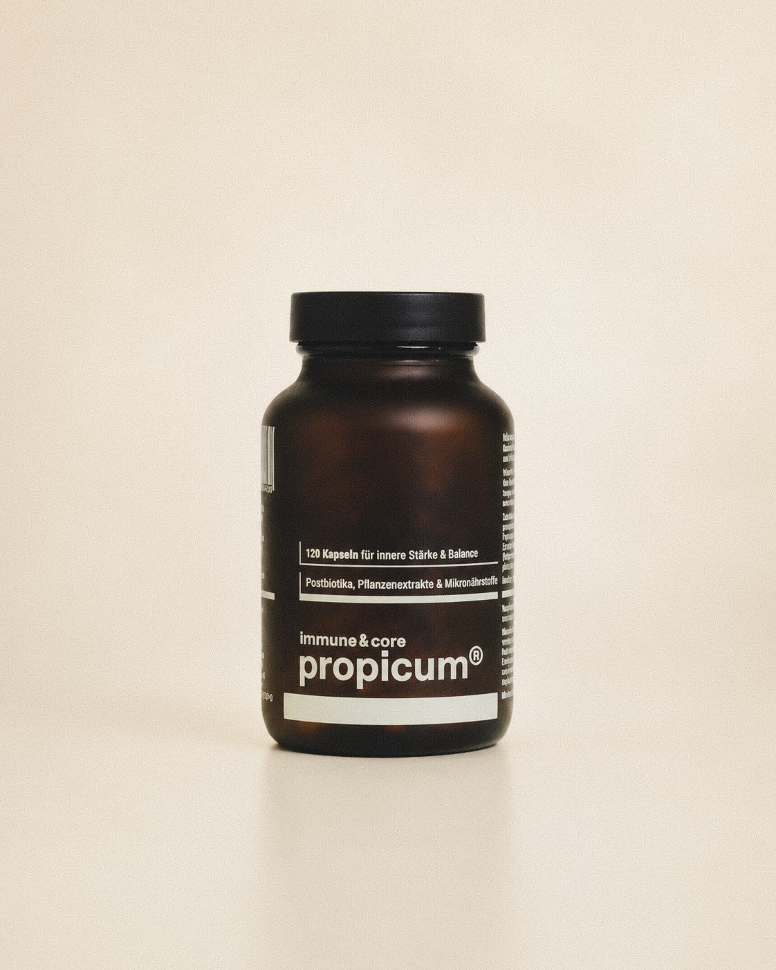 Dunkelbrauner Glasbehälter mit propicum immune & core steht vor beigem Hintergrund